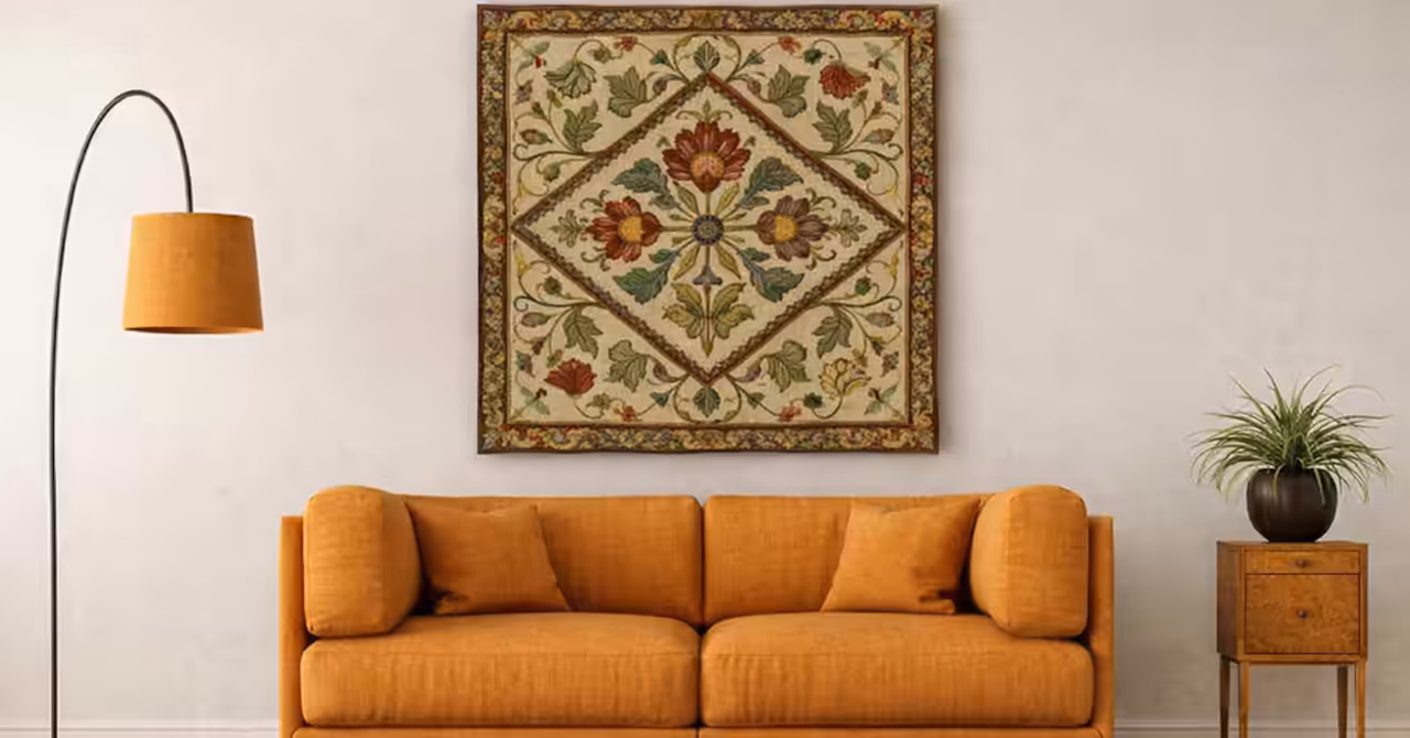 Arts and Crafts style embroidered wall hanging with floral motifs above a sofa in a warm-toned interior setting