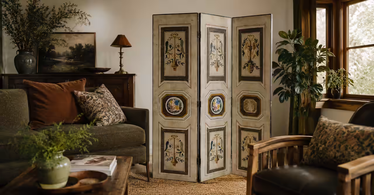 Arts & Crafts inspired living room featuring a vintage three-panel decorative screen in a warm modern interior with timber furniture and plants.